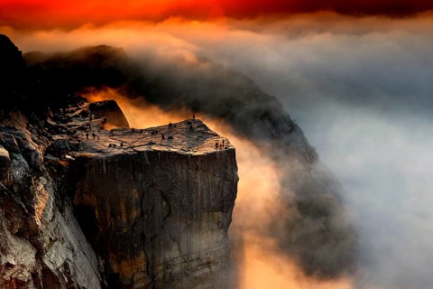 Dramatic view of Prekestolen at sunrise surrounded by clouds and fog