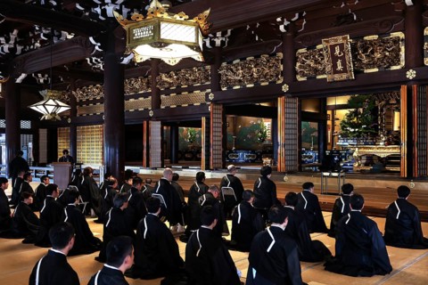 Interior view of Honganji Temple with monks meditating in traditional dress, Kyoto, Japan