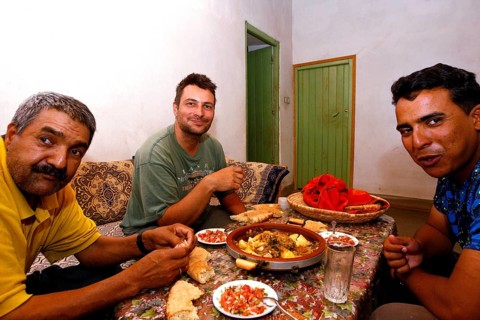 Three men enjoy a Moroccan dinner together with bread and a hearty dish, Errachidia, Morocco