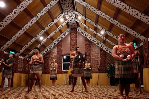 Maori dancers in traditional dress in an ornate meeting house, Rotorua, Te Puia, New Zealand