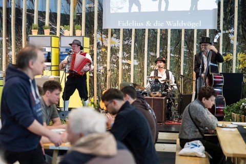 Visitors and the band Fidelius & die Waldvögel at the Green Week on the exhibition grounds in