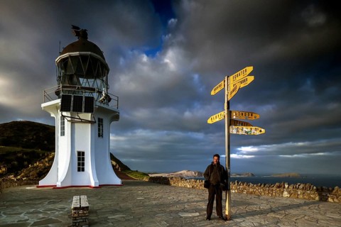 Lighthouse and yellow signpost at Cape Reinga under dramatic sky, Cape Reinga, Northland, New