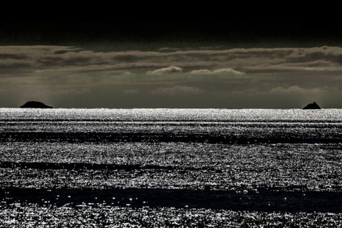 Waves reflect light and create an atmospheric image at dusk, Bay of Islands, New Zealand