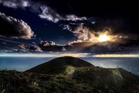 Sunset over the hills near Cape Reinga with rays of light through clouds, zero