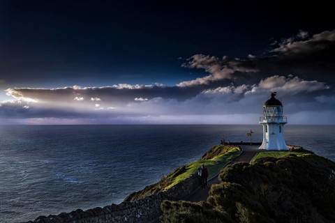 Lighthouse under a dramatic sky lights up the sea at Cape Reinga, Cape Reinga, Northland, New