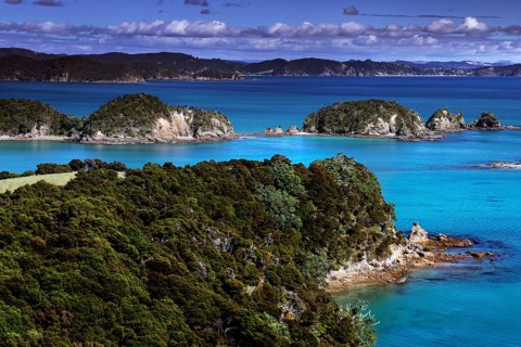 Lush vegetation and deep blue water characterize the landscape of Otehai Bay, Otehai Bay, Bay of
