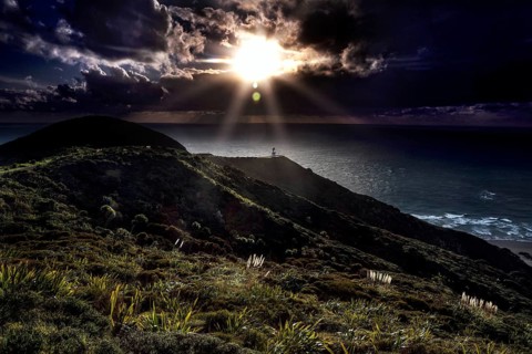 Darkness and sun rays at Cape Reinga with the lighthouse in the foreground, Cape Reinga, Northland,