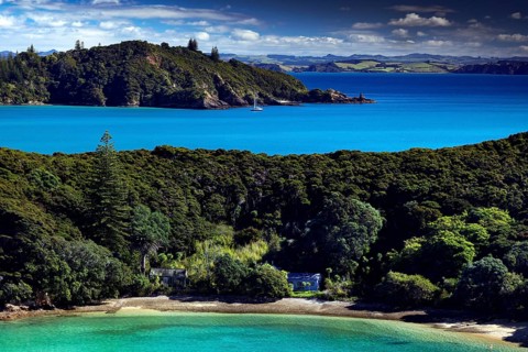 View of the green vegetation of Otehai Bay with blue sea and beach, Otehai Bay, Bay of Islands, New