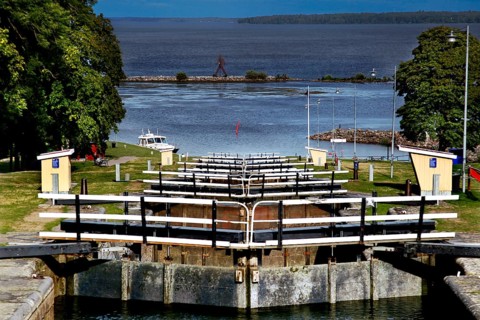 Lock system in the Göta Canal near mountain, with water and surrounding landscape under wide sky,