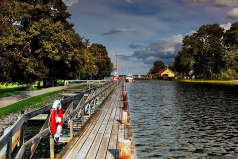 Long wooden walkway along the Göta Canal in a mountain, lined with trees and water under a cloudy