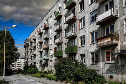 Rows of prefabricated buildings under cloudy sky with adjacent green areas, Liepaja, Karosta,