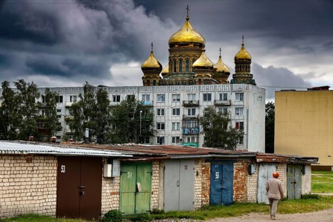 Prefabricated building in front of cathedral with golden domes and garages under dramatic sky,