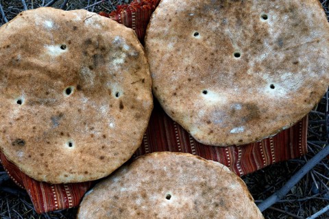 Three large flatbread loaves on a support in the desert, Beni Tajite, Morocco