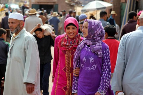 Smiling woman wearing lively traditional clothes at a busy market in Achaouikh, Achaouikh, Morocco