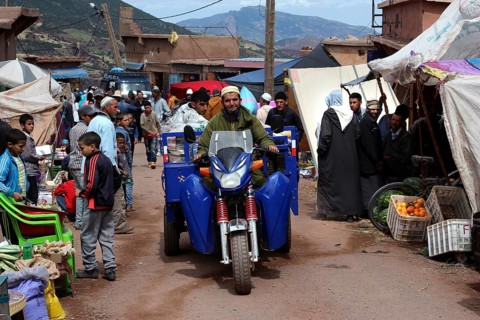 Busy market day in Achaouikh with people, vehicles and stalls, zero