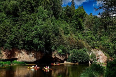 Lined river in Gauja National Park with canoe and steep rocks in the background, Gauja National