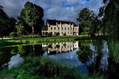 Kuldiga District Court with reflection in a quiet pond and surrounded by trees, Kuldiga, Courland,