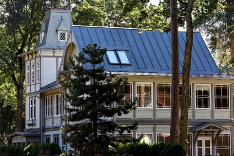 Elegant art nouveau wooden house with eye-catching blue roof under tall trees, Majori, Jurmala,