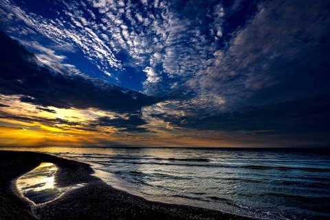 Sunset over sea with reflecting water under dramatic clouds, Kolka, Latvia