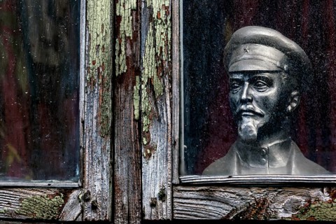 Lenin bust stands behind a dilapidated window in Kuldiga's old town, Kuldiga, Latvia