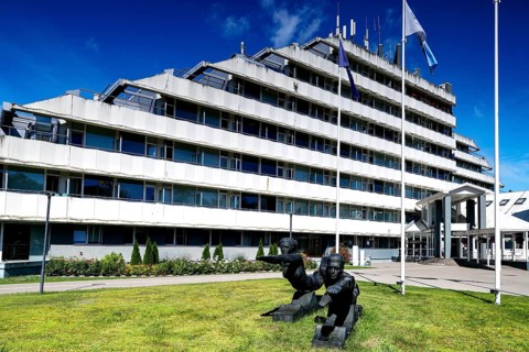 Modern sanatorium building with flags and well-kept green area against blue sky, Vaivari, Jurmala,