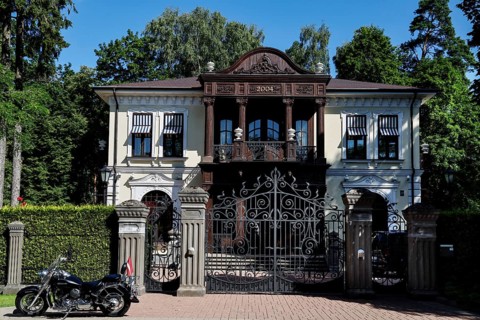 Large wooden house with ornate gate and parked motorcycle in front of it, Jurmala, Latvia
