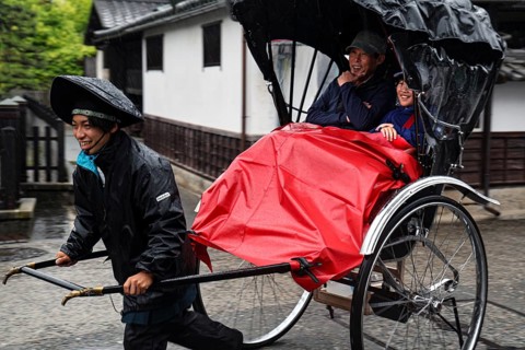 A rickshaw driver pulls two passengers through the streets of Kurashiki when it rains, Kurashiki,
