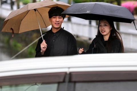 Smiling couple walking with umbrellas in the rain, Kurashiki, Okayama, Japan
