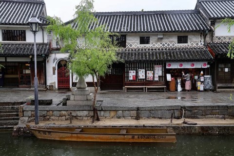 Traditional buildings along a canal in Kurashiki with a small boat in the foreground, Kurashiki,