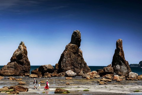 Large coastal rock formations under clear blue sky with walkers, Kushimoto, Japan
