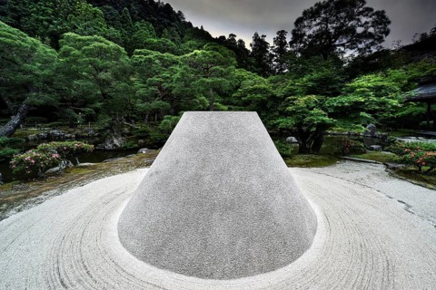 Zen garden with the cone-shaped sand hill Kogetsudai surrounded by green vegetation and trees,