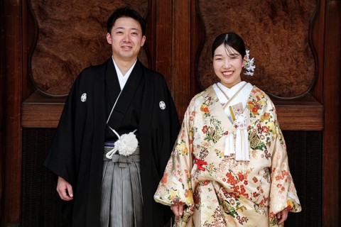 Bride and groom wearing traditional kimonos against a wooden background, Kyoto, Higashiyama, Japan