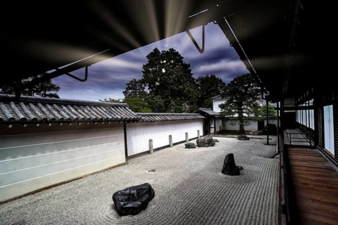 Zen garden with textured sand patterns and rocks surrounded by traditional Japanese architecture,