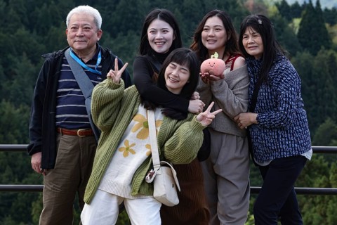 A group of tourists poses happily against a picturesque backdrop in Magome, Magome, Japan