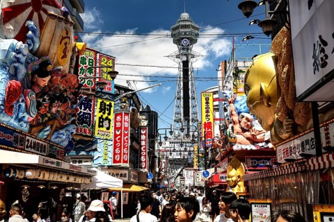 Bustling street in Shinesekai with the Tsutenkaku Tower in the background, Osaka, Japan