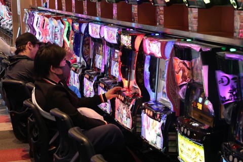 Men focus on glowing pachinko machines, Osaka, Japan