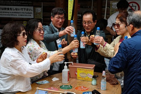 Friends at Kamado Jigoku in Beppu toast with bottles and enjoy the atmosphere, Beppu, Oita, Japan