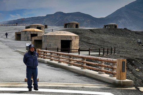 A bunker and rangers stand in the dramatic volcanic landscape of Nakadake, Aso, Aso, Kyushu, Japan