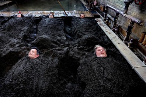 People lie in a sand bath at Takegawara Onsen in Beppu, Beppu, Oita, Japan