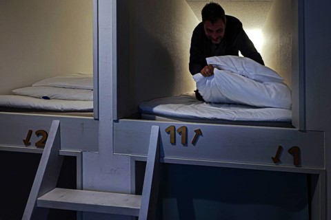 Man in sleeping capsule in a Japanese capsule hotel. Cozy and compact accommodation, Ise, Mie,