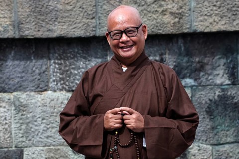 Smiling monk wearing traditional robe at Kotokuin Temple in Kamakura, Kamakura, Japan