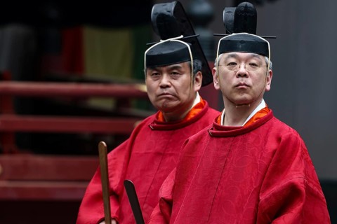 Two priests in traditional red robes and wearing Kanmuri hats in the courtyard of Toshogu Shrine,