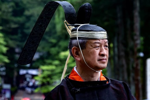 Man wearing traditional clothing and distinctive head covering during a cultural festival in Nikko,