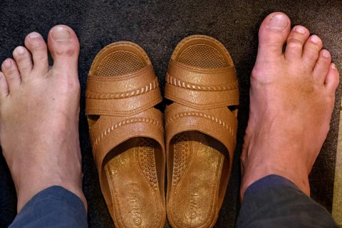 Two feet next to a pair of brown toilet shoes on dark ground, Osaka, zero, Japan