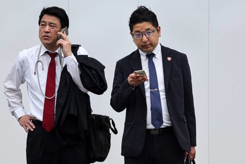 Two businessmen in suits, one talking on the phone, the other using a smartphone, Tokyo, Minato,