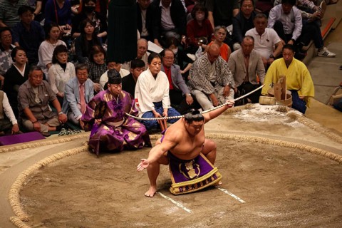 Sumo wrestlers in traditional ceremony in Kokugikan surrounded by spectators, Tokyo, Ryogoku, Japan