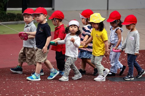 Kindergarten group wearing red caps walking on a playground, Tokyo, Minato, Japan