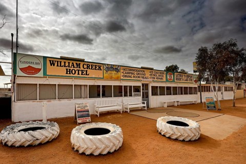 In front of William Creek Hotel with big tires under dramatic sky, William Creek, South Australia,