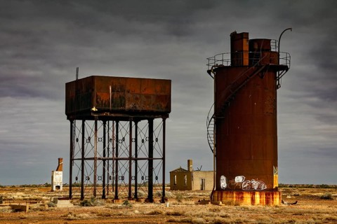 Rusty water towers and orphaned buildings under cloudy outback sky, Oodnadatta Track, null,