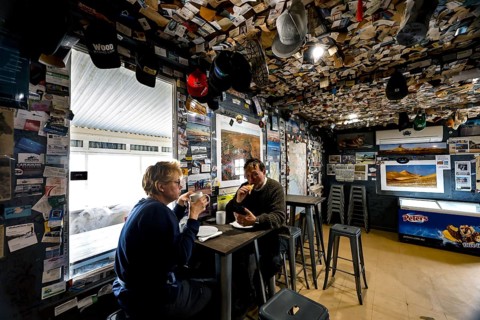 Two people in the warmly decorated and cozy interior of the William Creek Hotel, William Creek,